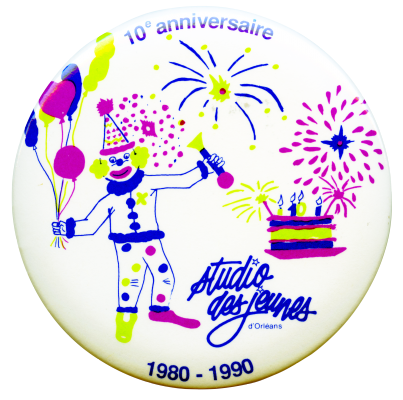 Photographie d’un macaron sur lequel figurent, sur fond blanc, un clown tenant des ballons, un gateau d'anniversaire et un feu d'artifice en bleu, vert clair et fuhsia. Le nom de l'organisme apparaît en bleu, ainsi que la mention de l'anniversaire.