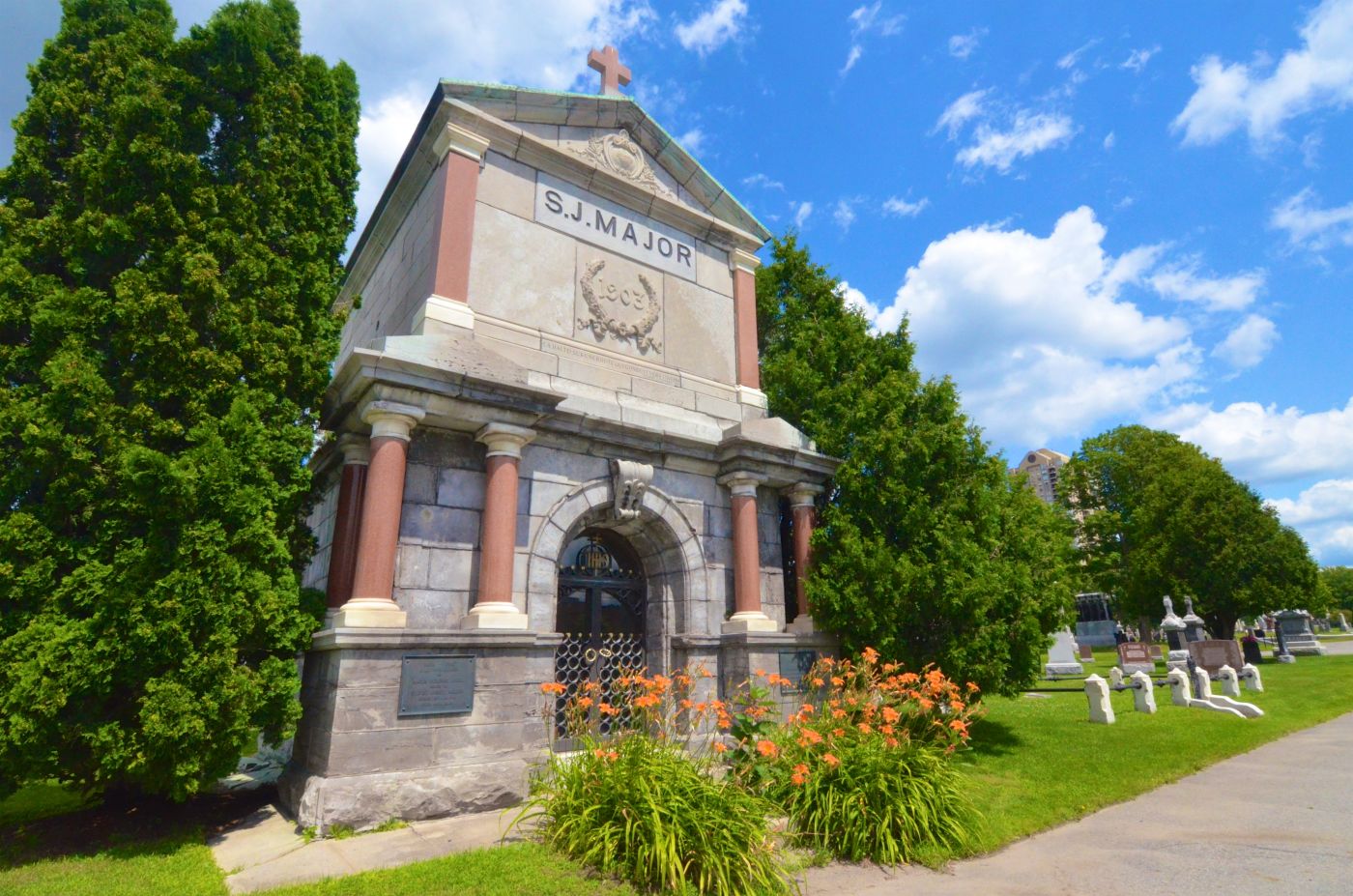 Colour photograph of a very large stone monument, in a cemetery. The  monument is adorned by marble colomns and topped by a cross. Engraved in stone, the inscription S.J. Major, and below, 1903.