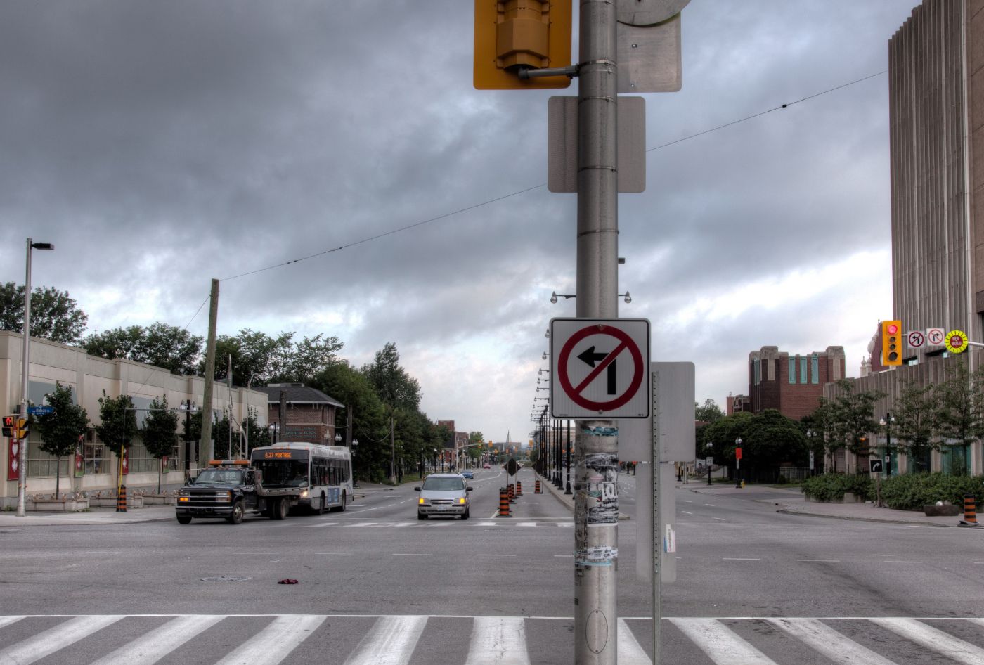 Photographie en couleur d’un boulevard à six voies. On peut y voirdes voitures, un autobus et des panneaux routiers. Un édifice à plusieurs étages et d’autres immeubles récents font aussi partie du paysage.